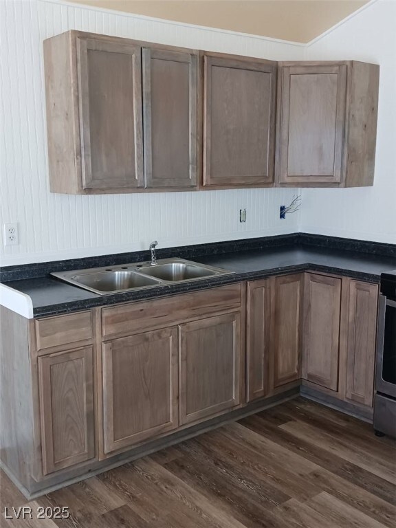 kitchen with a sink, dark countertops, dark wood-style floors, and range