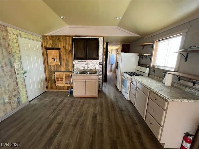 kitchen featuring white gas range oven, a sink, open shelves, dark wood-style floors, and lofted ceiling