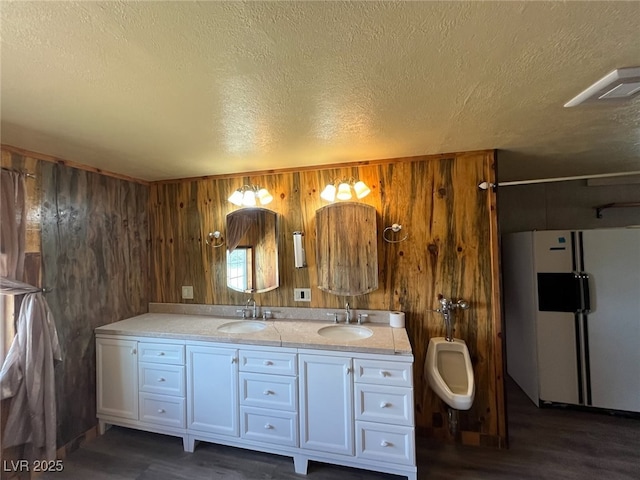 full bath with double vanity, wood walls, and a sink