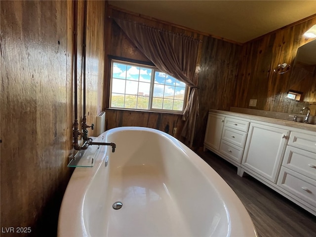 full bath featuring a soaking tub, wood walls, and vanity