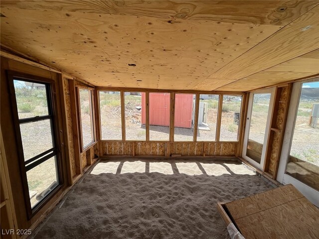 unfurnished sunroom with vaulted ceiling and carpet flooring