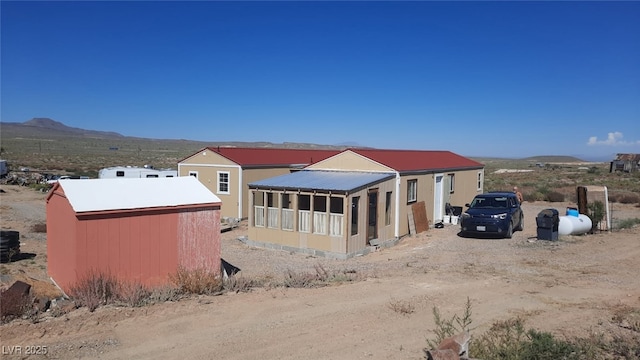 exterior space featuring an outbuilding, metal roof, a mountain view, and dirt driveway