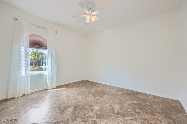 spare room with baseboards and a ceiling fan