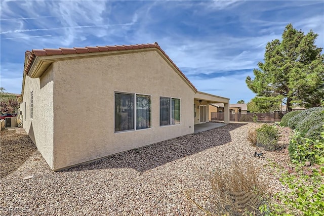 back of property featuring a patio, fence, central AC, stucco siding, and a tiled roof