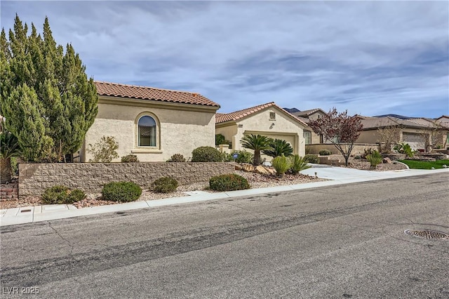mediterranean / spanish-style home with stucco siding, concrete driveway, an attached garage, and a tiled roof