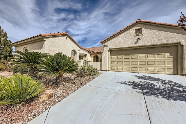 mediterranean / spanish home with stucco siding, a garage, driveway, and a tile roof