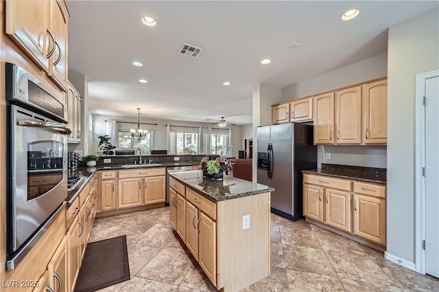 kitchen featuring visible vents, light brown cabinets, appliances with stainless steel finishes, a peninsula, and a sink