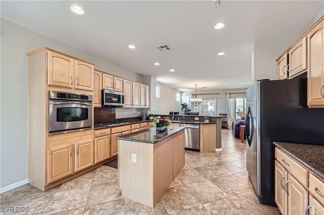 kitchen featuring light brown cabinets, visible vents, a peninsula, stainless steel appliances, and a center island