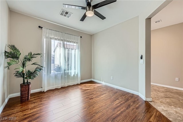 spare room featuring wood finished floors, visible vents, and ceiling fan