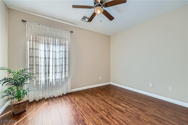 empty room featuring wood finished floors, visible vents, a wealth of natural light, and ceiling fan