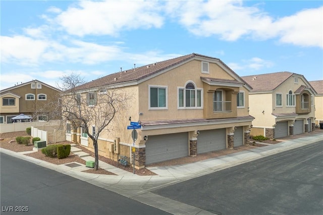 view of front facade featuring an attached garage, fence, stone siding, and stucco siding