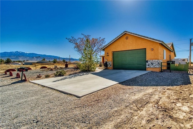 3424 Mount Charleston Dr, Pahrump, NV 89048 - view of side of home featuring stone siding, a mountain view, concrete driveway, stucco siding, and a garage