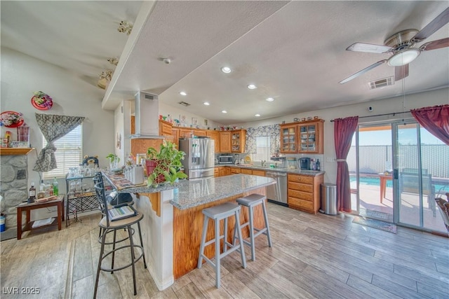 3424 Mount Charleston Dr, Pahrump, NV 89048 - kitchen featuring wall chimney range hood, appliances with stainless steel finishes, light wood finished floors, ceiling fan, and recessed lighting