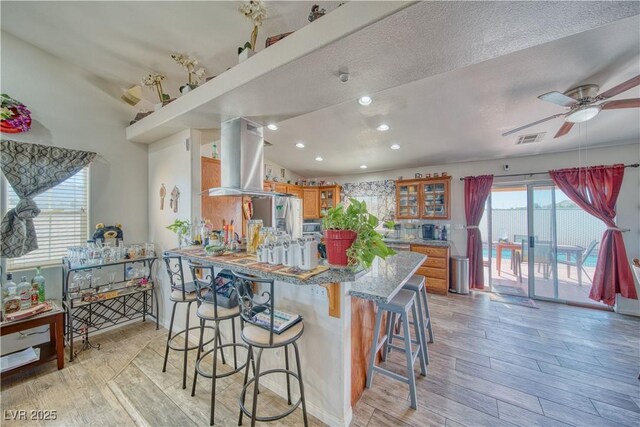 3424 Mount Charleston Dr, Pahrump, NV 89048 - kitchen with extractor fan, brown cabinets, light wood-style floors, a breakfast bar area, and recessed lighting