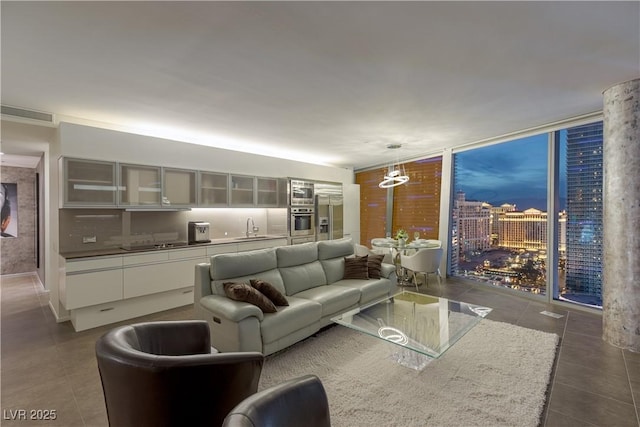 living area with dark tile patterned floors, a notable chandelier, expansive windows, and visible vents