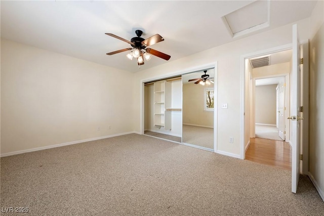 unfurnished bedroom featuring attic access, carpet flooring, baseboards, visible vents, and a closet