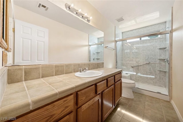 bathroom with toilet, vanity, a shower stall, tile patterned flooring, and visible vents