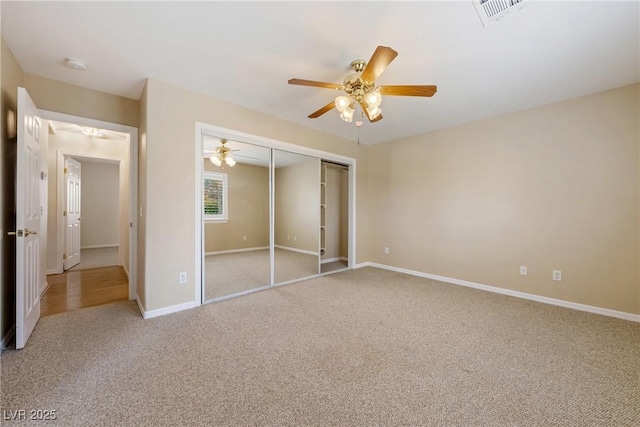 unfurnished bedroom with a closet, baseboards, visible vents, ceiling fan, and carpet
