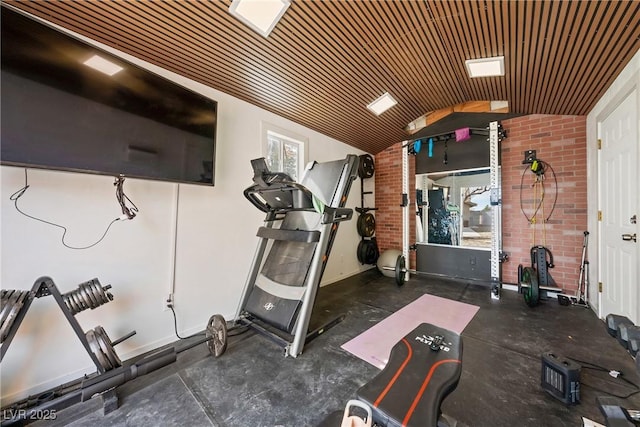 exercise room featuring baseboards, vaulted ceiling, wooden ceiling, and brick wall