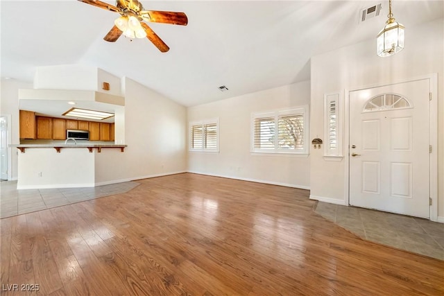 unfurnished living room featuring a ceiling fan, baseboards, light wood finished floors, and visible vents