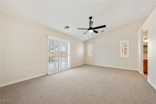 spare room featuring light carpet, lofted ceiling, baseboards, visible vents, and ceiling fan