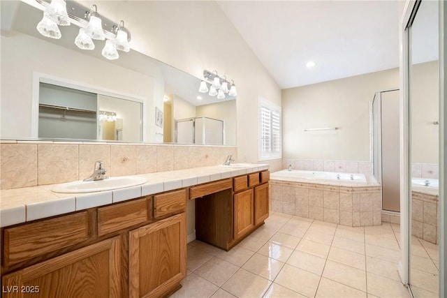 full bath featuring tile patterned flooring, vaulted ceiling, a shower stall, a sink, and a garden tub