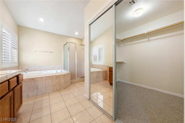 full bathroom featuring a stall shower, vanity, a walk in closet, tile patterned flooring, and visible vents