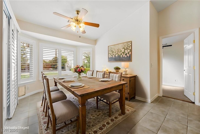 dining room featuring baseboards, lofted ceiling, ceiling fan, and light tile patterned floors