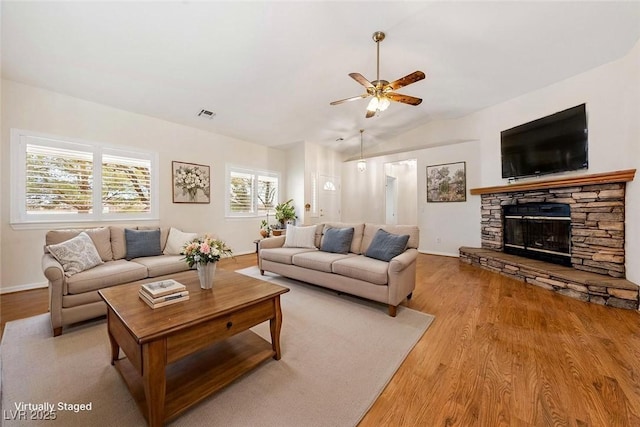 living room featuring visible vents, a fireplace, wood finished floors, and a ceiling fan