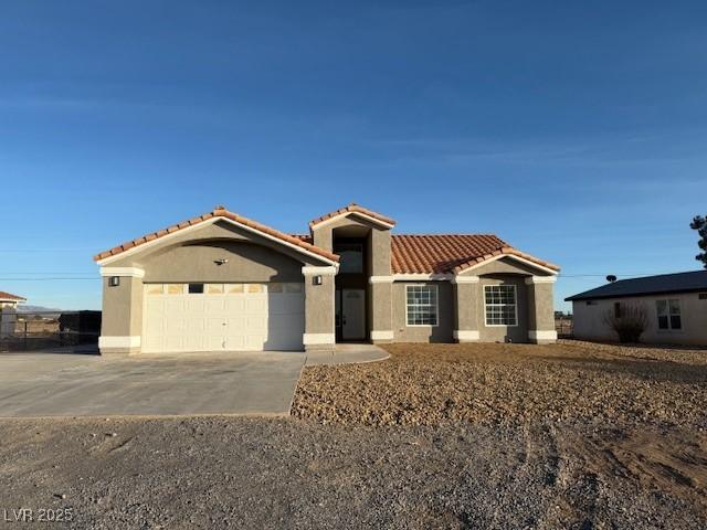 mediterranean / spanish-style home with stucco siding, concrete driveway, an attached garage, and a tiled roof