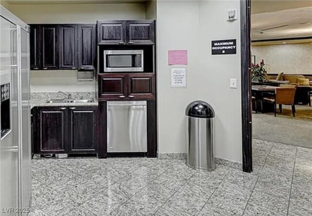 kitchen featuring stainless steel appliances, dark cabinets, and a sink