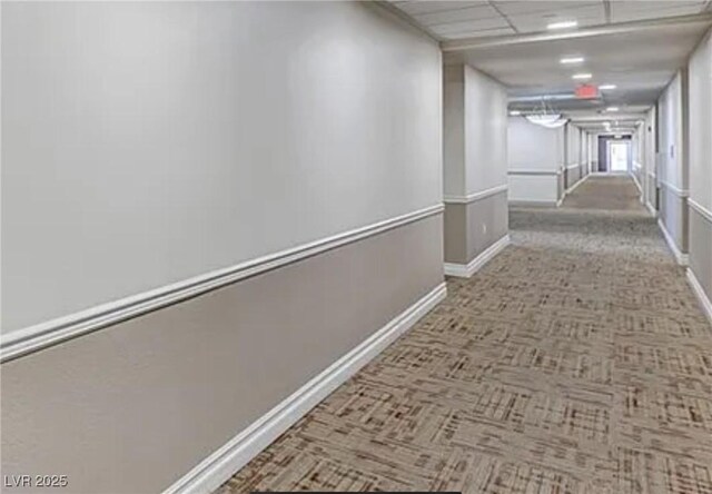 corridor with baseboards and carpet