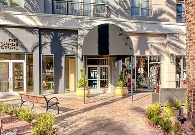 entrance to property with french doors, a balcony, and stucco siding