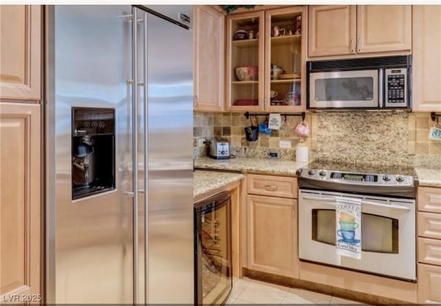kitchen with light stone counters, stainless steel appliances, decorative backsplash, and glass insert cabinets