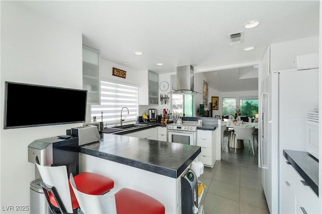 6923 Emerald Springs Ln, Las Vegas, NV 89113 - kitchen featuring a peninsula, dark countertops, wall chimney exhaust hood, electric stove, and white refrigerator with ice dispenser