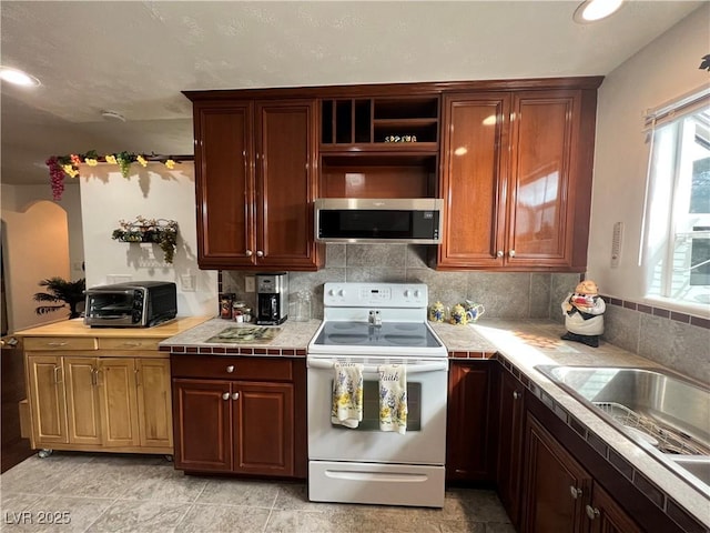4861 Pahrump Valley Blvd, Pahrump, NV 89048 - kitchen featuring decorative backsplash, a toaster, stainless steel microwave, a sink, and white range with electric cooktop