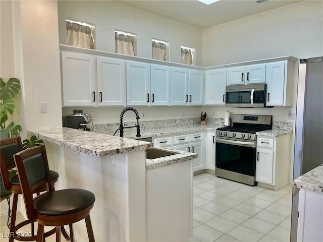 2736 Darby Falls Dr, Las Vegas, NV 89134 - kitchen with stainless steel appliances, a peninsula, a kitchen breakfast bar, white cabinets, and light tile patterned floors
