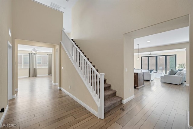 stairway featuring baseboards, wood finished floors, and a ceiling fan