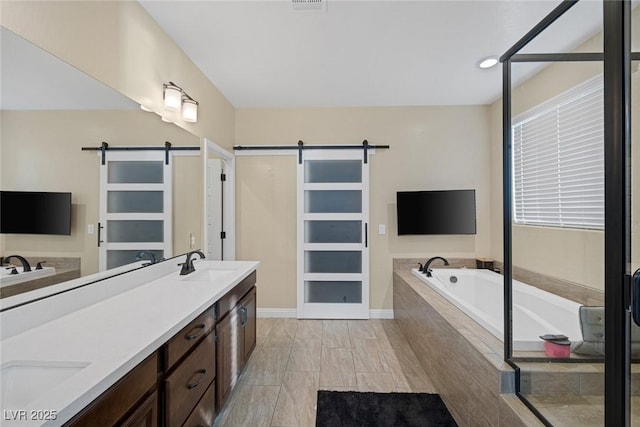 full bath with a bath, double vanity, and a sink