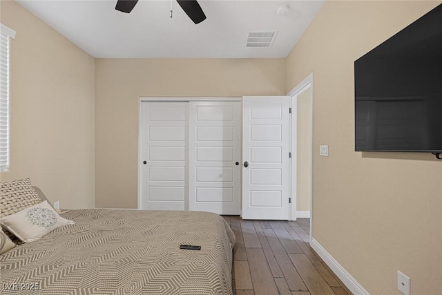 unfurnished bedroom featuring baseboards, ceiling fan, visible vents, a closet, and wood finished floors