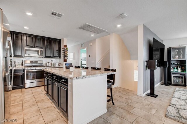 105 Campbelltown Ave, Henderson, NV 89015 - kitchen with a kitchen island, a breakfast bar area, tasteful backsplash, appliances with stainless steel finishes, and visible vents