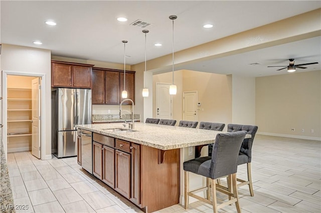 1004 Bluebird Ridge Ct, North Las Vegas, NV 89084 - kitchen featuring stainless steel appliances, a breakfast bar area, open floor plan, a center island with sink, and ceiling fan