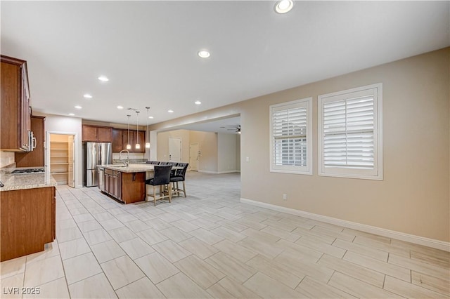 1004 Bluebird Ridge Ct, North Las Vegas, NV 89084 - kitchen featuring open floor plan, freestanding refrigerator, a breakfast bar area, a kitchen island with sink, and brown cabinets