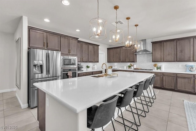 505 Punto Vallata Dr, Henderson, NV 89011 - kitchen with a chandelier, stainless steel appliances, wall chimney range hood, visible vents, and decorative backsplash