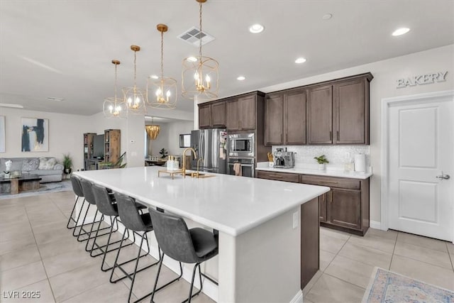 505 Punto Vallata Dr, Henderson, NV 89011 - kitchen featuring an inviting chandelier, light tile patterned floors, stainless steel appliances, visible vents, and dark brown cabinets