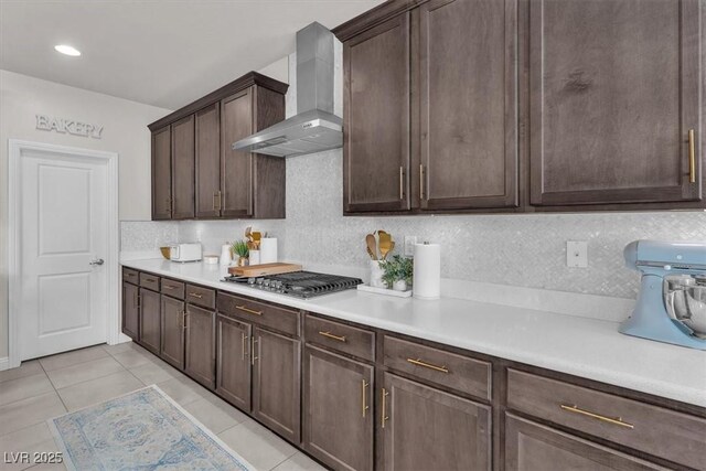 505 Punto Vallata Dr, Henderson, NV 89011 - kitchen with light countertops, tasteful backsplash, stainless steel gas stovetop, dark brown cabinetry, and wall chimney exhaust hood
