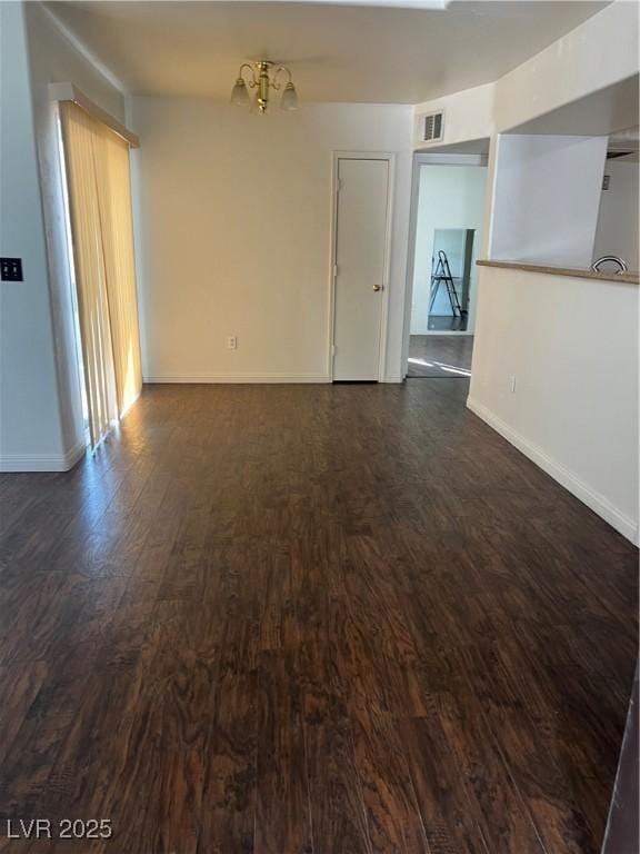 spare room with dark wood-type flooring, visible vents, baseboards, and a notable chandelier