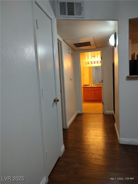 corridor with visible vents, baseboards, and wood finished floors