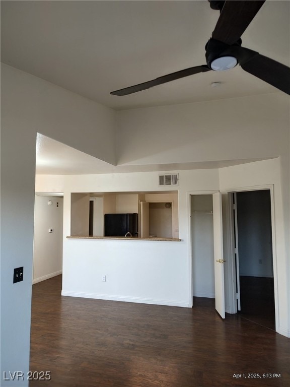 empty room featuring visible vents, baseboards, and dark wood finished floors