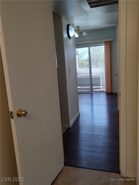 hall with visible vents, baseboards, and wood finished floors